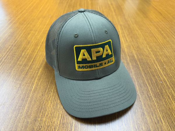 Gray cap with yellow APA logo on a wooden surface