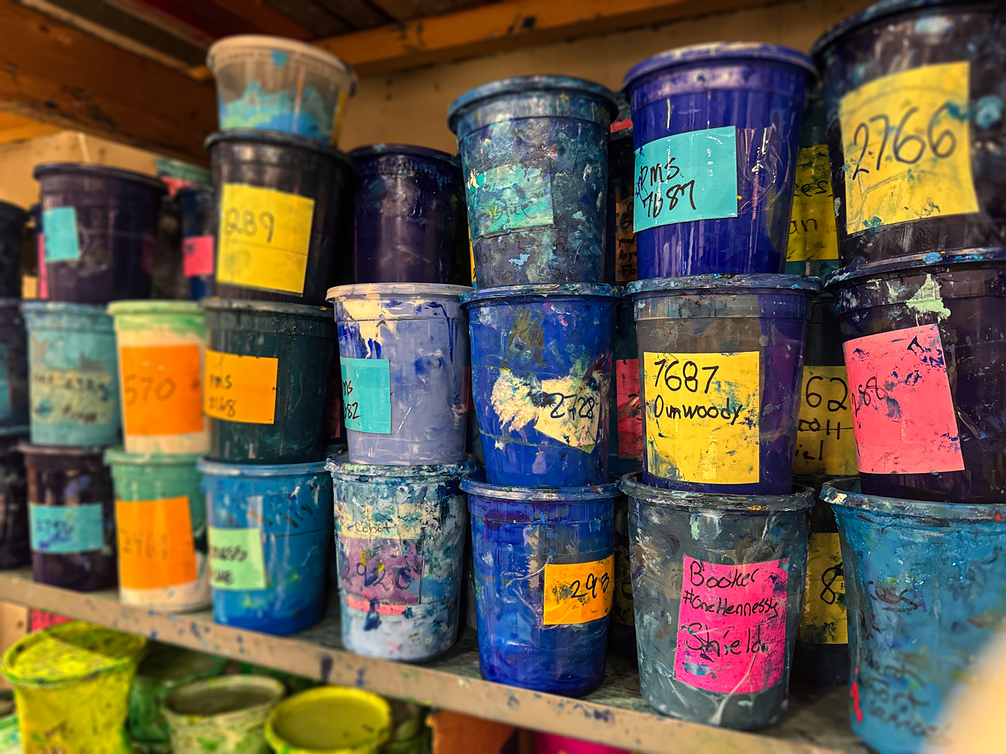 Stack of colorful plastic containers with labels on a shelf